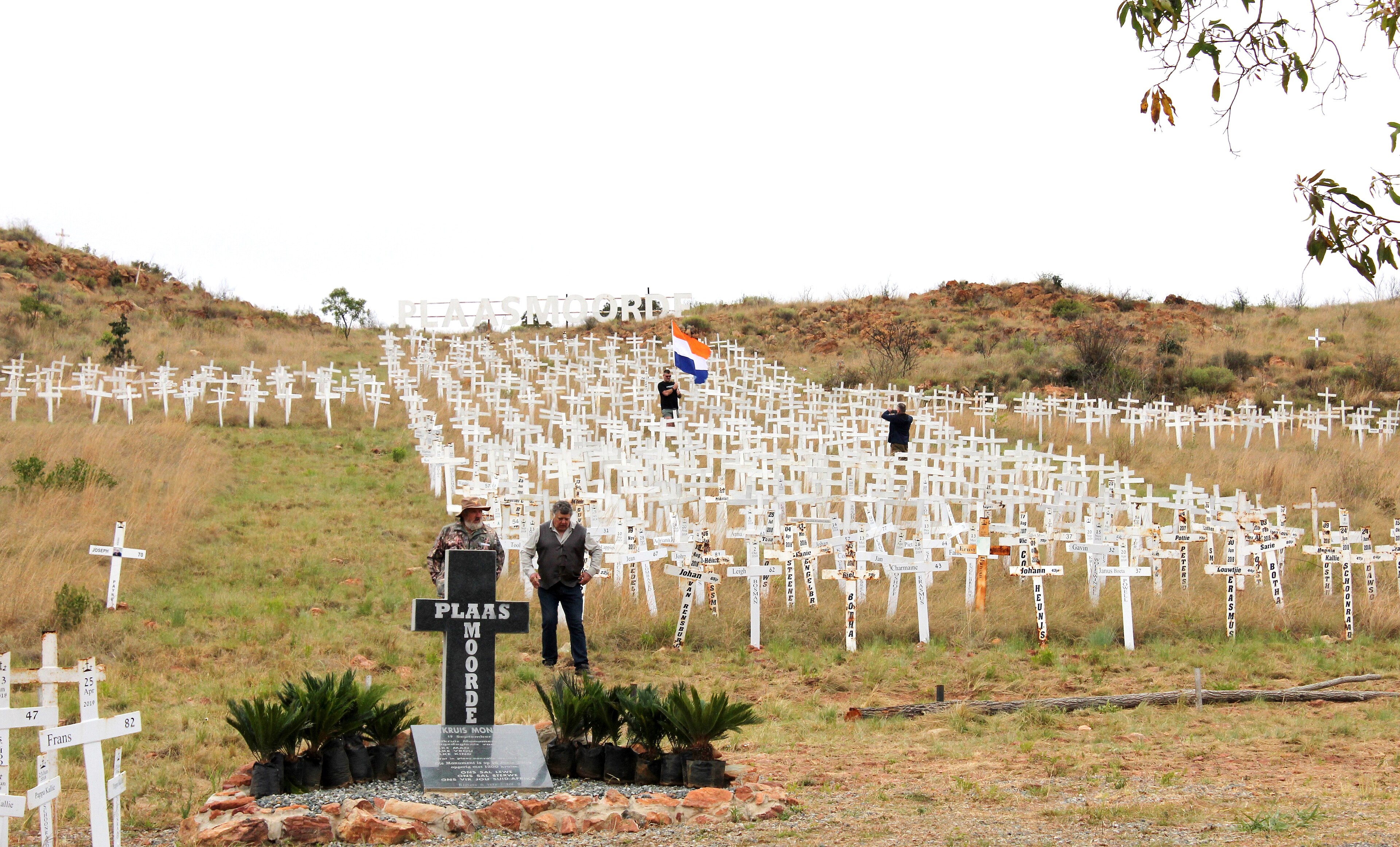 Visitors walk among crosses at Witkruis. The memorial commemorates white farmers and relatives murdered in attacks on South African farms, identifying victims through names and dates.